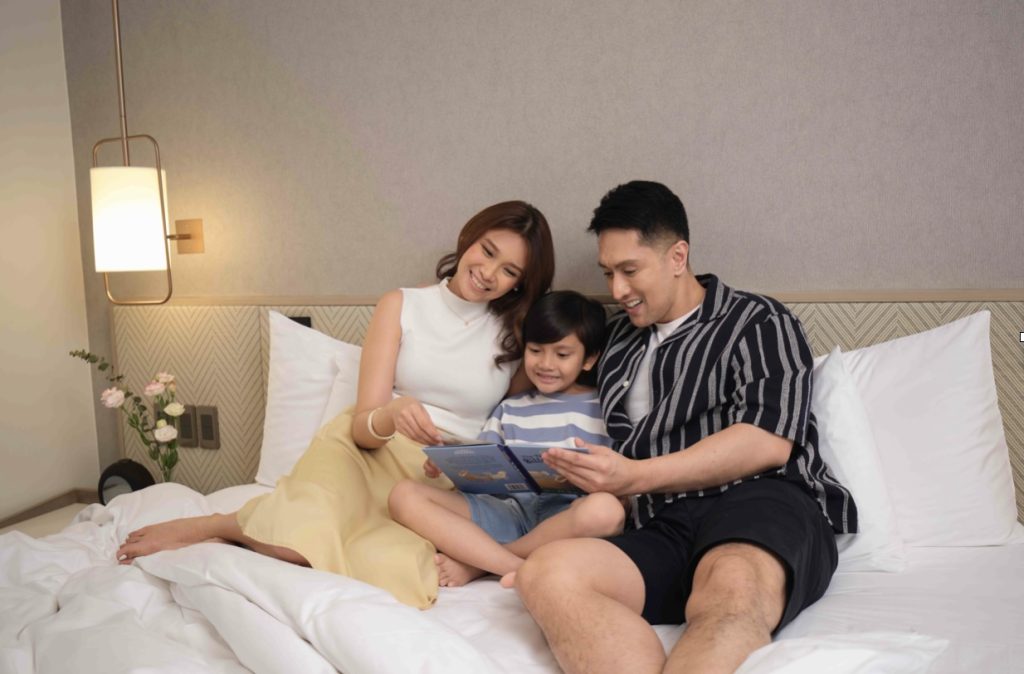 Easter Adventure of a family of a wife, husband, and a son reading a book while in bed.